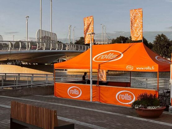 Mastertent brändätty 8x4 kokoinen pop-up teltta, jossa liput katolla. Oranssi teltta moottoriurheilu tapahtumassa.